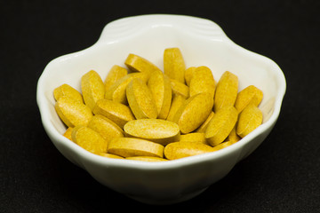 Capsules, tablets and gelatin-shaped medicines in oyster-shaped bowls on black background