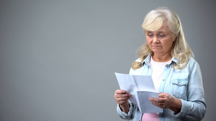 Unhappy elderly woman reading letter, receiving bad news, health test results