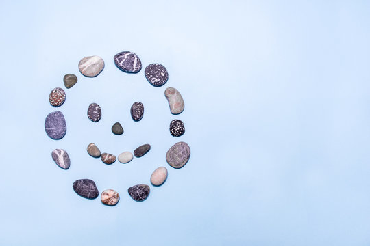 Beach pebbles made into a smiling face on a blue background. Concepts for health, happiness, healing, wellness. copy space. top view.