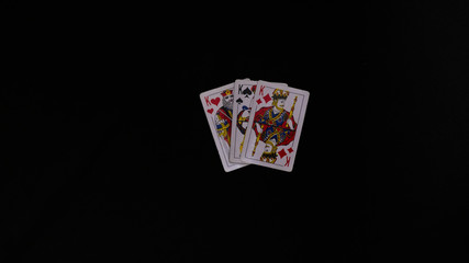 playing cards on a black table, hands holding cards