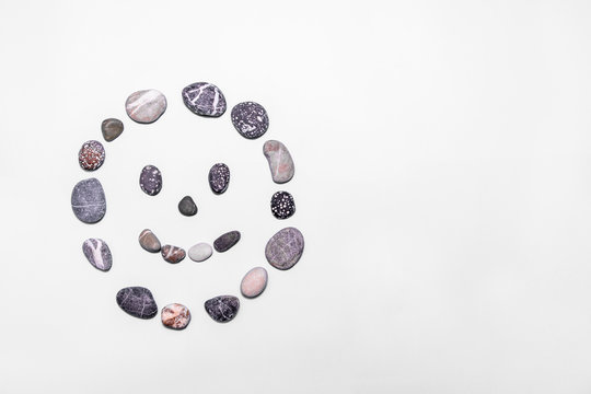 Beach pebbles made into a smiling face on a white background. Concepts for health, happiness, healing, wellness. copy space. top view.