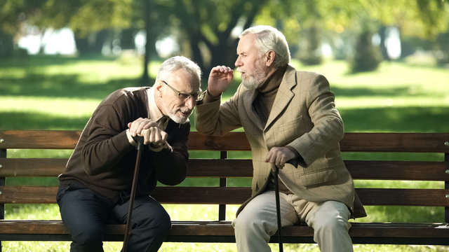 Senior gentlemen talking to his hearing impairment old friend, health problems