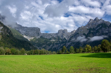 Austrian Verfenveg village Alps mountains autumnal scenery with fog, green meadows and rocks