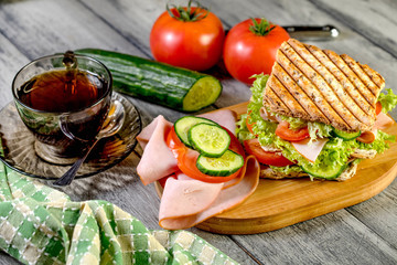 Sandwich with ham, cucumber, tomato and lettuce.