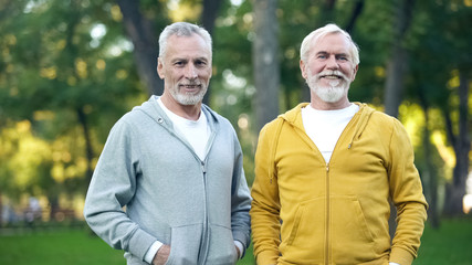 Two senior sportsmen smiling in camera, active lifestyle, health care, wellness