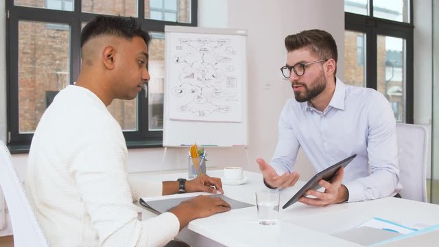 technology, business and employment concept - employer or hr manager having interview with indian male employee at office