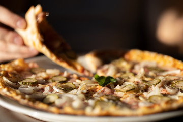 Man's hand holding a slice of Pizza