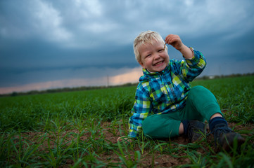 Naklejka na ściany i meble happy children playing in field sown with winter wheat against backdrop of rain clouds. Brothers have fun on vacation in village. Tradition of respect for nature, sports and harmonious life.