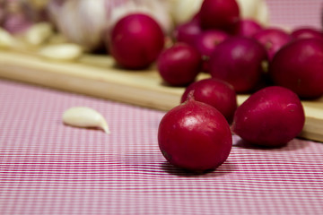 Healthy vegetables on a pink background. Fresh garlic (allium, Bulbus Allii Sativ) is a real storehouse of nutrients and trace elements. Red sweet onions (solaninum) - natural antioxidant. Red radish 
