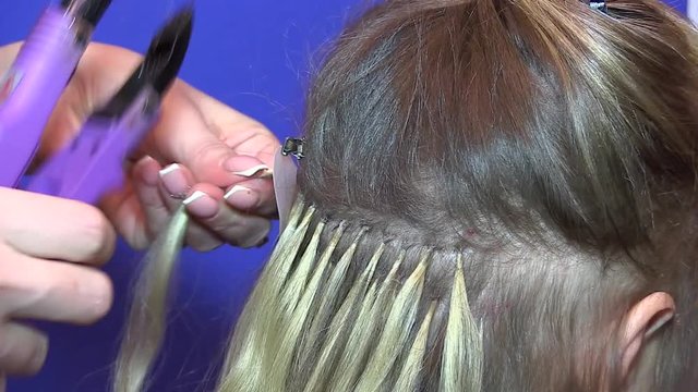 Стоковое видео  Hairdresser hair extensions brunette girl. Braiding braids for subsequent hair extensions
