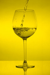 Filling the glass, pouring wineglass on yellow background