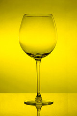 Empty wine glass on yellow background, empty wineglass