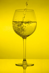 Filling the glass, pouring wineglass on yellow background