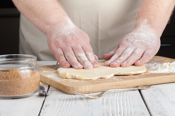 cooking and home concept - close up of hands making cookies from fresh dough at home