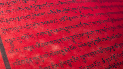 Tibetan letters on red textile. Religious writing. Prayer flags. Mantra. Buddhism.