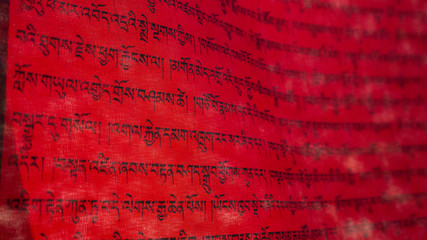 Tibetan letters on red textile. Mantra. Calligraphy