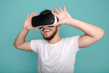 Cheerful bearded man trying VR headset and exploring another world on the colorful background.
