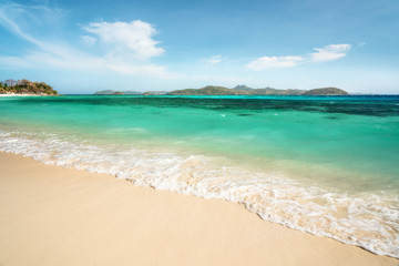 Fototapeta na wymiar Tropical Malcapuya island with sea foam, azure water and white sand beach. Travel vacation at Philippines.