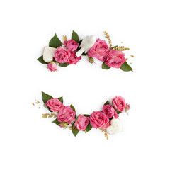 Floral frame wreath of rose flower buds, leaves and romantic decorations on white background mockup. Flat lay, top view.