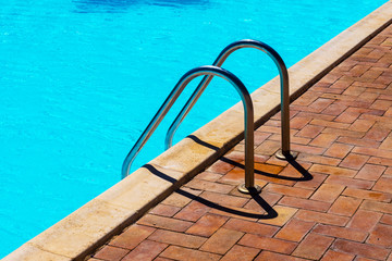 Grab bars ladder in the blue swimming pool