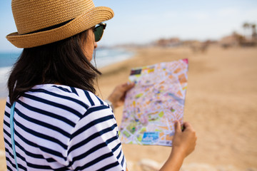 young indian woman looking at the map in front of the sea