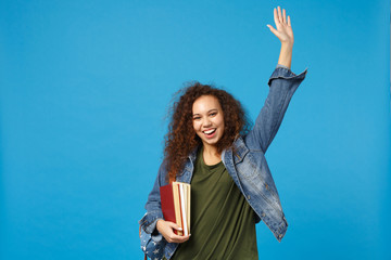 Young african american girl teen student in denim clothes, backpack hold books isolated on blue...