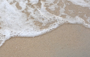 Fototapeta na wymiar Beautiful soft waves of Blue Ocean with Sandy Beach Background close up. Sea sand wallpaper