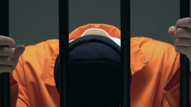Desperate prisoner with scars on face holding cell bars, death penalty waiting