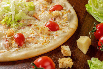 Pizza Caesar close-up on a wooden table next to tomato crackers and iceberg lettuce.