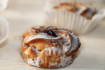 Chocolate muffins on a wooden background, closeup. Selective focus. Delicious muffins sprinkled with powdered sugar in paper cups