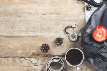 Hiking Backpack, compass, belt and other camping gear on a wooden background. The concept of hiking in the mountains or the forest, tourism, tent rest, camp. Flat lay, top view.