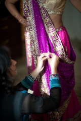 Fototapeta na wymiar Bridesmaid pinning indian bride's sari