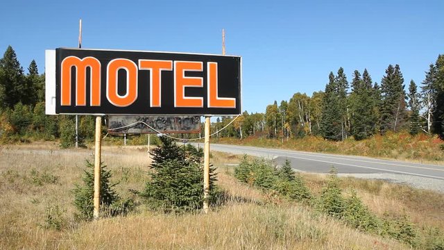 Old motel sign by side of the road. Traffic passes. Hwy 17, North of Wawa, Ontario, Canada.