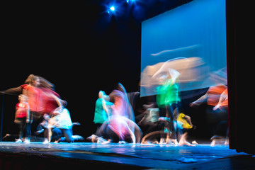 Group of dancer in colored clothes dancing on the stage in long exposure