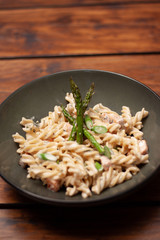 Pasta con crema y espárragos servido en plato de cerámica en mesa de madera