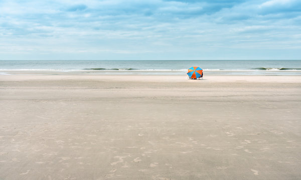 One beach umbrella for tourists on a wide, sandy beach