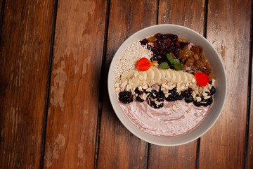 Bowl con desayuno saludable de yogurt con frutos secos, plátano, avena, zarzamoras y açai
