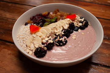 Bowl con desayuno saludable de yogurt con frutos secos, plátano, avena, zarzamoras y açai
