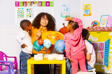 Diverse kids group learn planets in nursery school