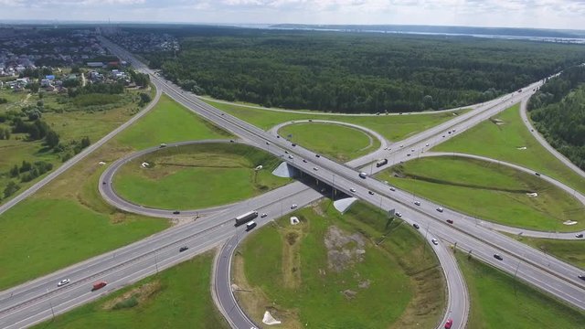 Traffic interchange. Top view of the road, city and forest. Summer video from the drone.