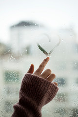 Depressed young woman near window at home, closeup 