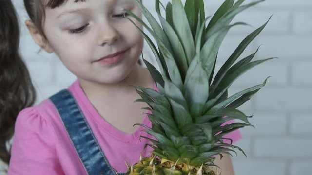 Portrait of a kid with pineapple. Beautiful little girl with a big pineapple.