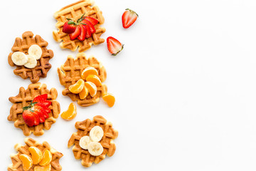 Homemade Viennese waffles with strawberry, tangerine and banana topings on white background top view make up