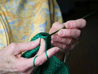 Grandmothers hands crochet green yarn. Closeup clip of senior woman and her crocheting handiwork.