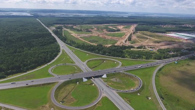 Traffic interchange. Top view of the road, city and forest. Summer video from the drone.