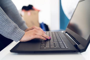 Close Up on woman's hands woman using laptop on the white table typing on the black keyboard at work office