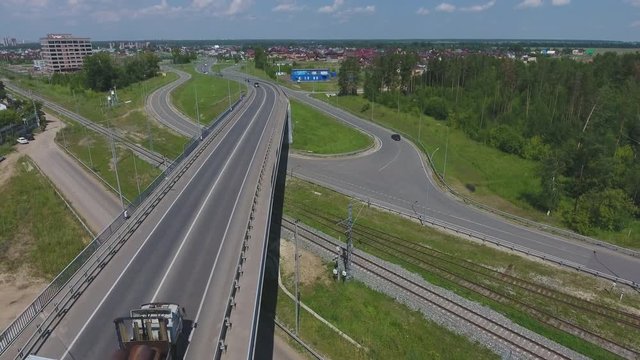 Transport interchange. Movement of cars on the bridge. Crossing the road. Top view of the road, city and forest. Summer video from the drone.