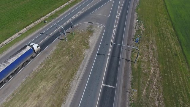 The intersection of highways. The movement of cars on the road. Top view of the intersection, cars, field and river. Summer video from the drone. Rural landscape.