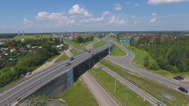 Transport interchange. Movement of cars on the bridge. Crossing the road. Top view of the road, city and forest. Summer video from the drone.