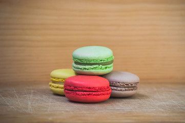Colorful tasty french macarons isolated on wood texture